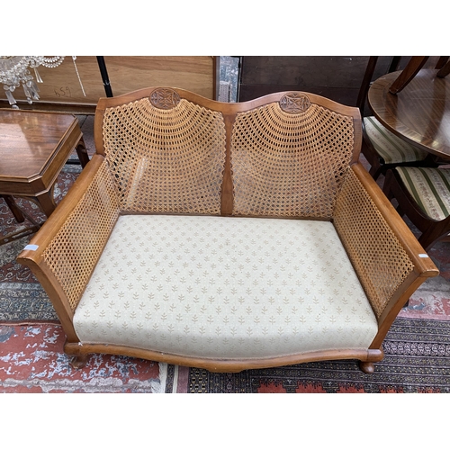 99 - A carved beech and rattan two seater bergere sofa - approx. 77cm high x 121cm wide x 74cm deep