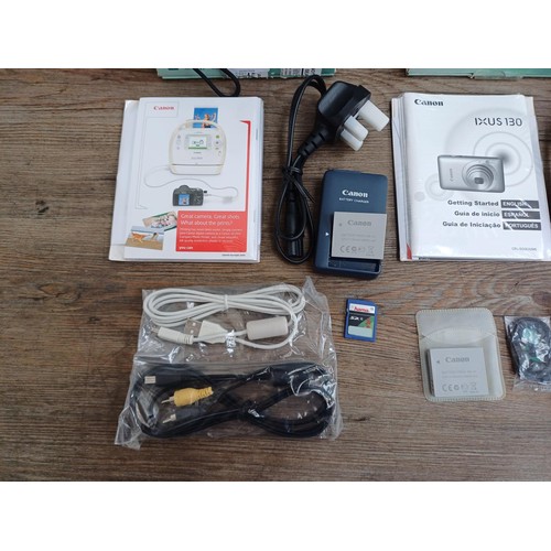 627 - Two boxed Canon IXUS 130 14.1mp compact digital cameras with batteries, chargers, software discs and... 