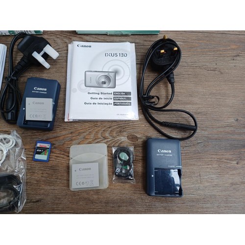 627 - Two boxed Canon IXUS 130 14.1mp compact digital cameras with batteries, chargers, software discs and... 