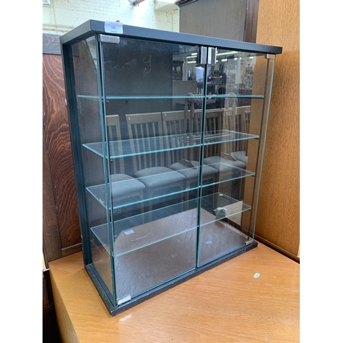 131 - A modern black laminate and glass two door display cabinet - approx. 72cm high x 61cm wide x 25cm de... 