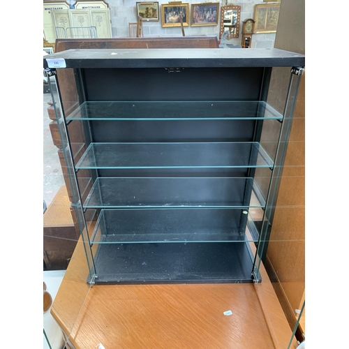 131 - A modern black laminate and glass two door display cabinet - approx. 72cm high x 61cm wide x 25cm de... 