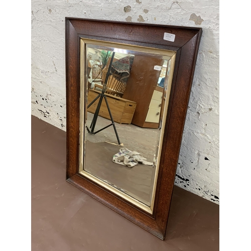 223A - A late 19th/early 20th century oak framed bevelled edge wall mirror - approx. 78cm high x 58cm wide