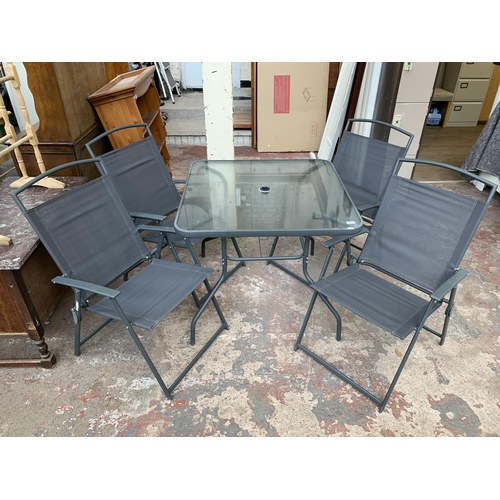 43 - A grey metal five piece patio set comprising four folding chairs and glass topped table - approx. 72... 