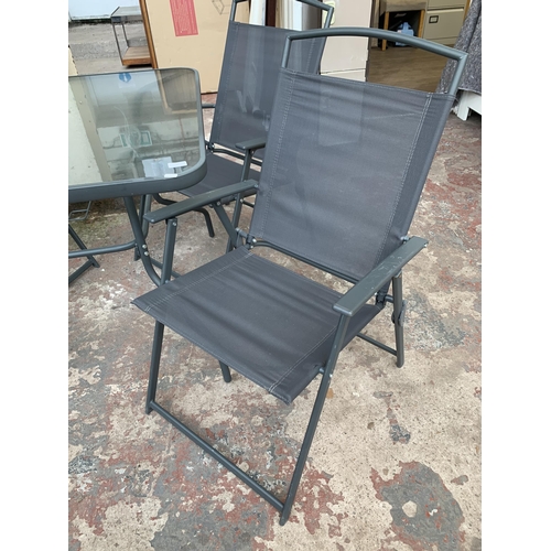 43 - A grey metal five piece patio set comprising four folding chairs and glass topped table - approx. 72... 