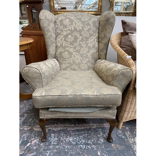 74 - A Victorian style floral fabric upholstered wingback armchair on cabriole supports