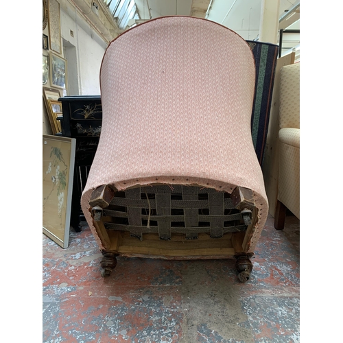 79 - A late 19th/early 20th century fabric upholstered armchair on turned wooden supports and castors