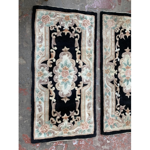 93 - Three black and cream floral pattern rugs - approx. 150cm x 72cm