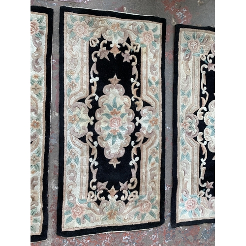 93 - Three black and cream floral pattern rugs - approx. 150cm x 72cm