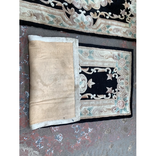 93 - Three black and cream floral pattern rugs - approx. 150cm x 72cm