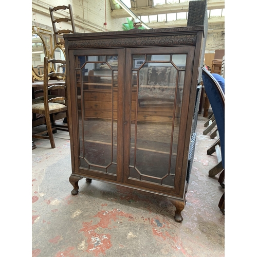 95 - An early 20th century carved oak display cabinet on cabriole supports - approx. 111cm high x 77cm wi... 