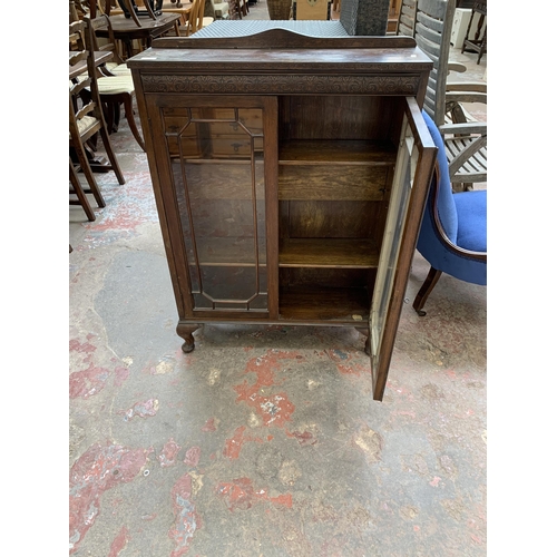 95 - An early 20th century carved oak display cabinet on cabriole supports - approx. 111cm high x 77cm wi... 