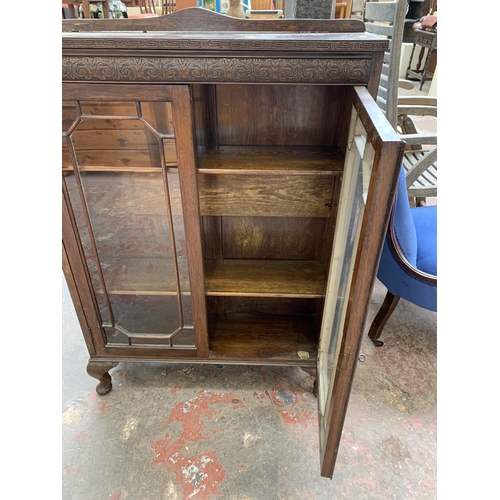 95 - An early 20th century carved oak display cabinet on cabriole supports - approx. 111cm high x 77cm wi... 