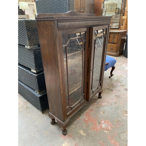 95 - An early 20th century carved oak display cabinet on cabriole supports - approx. 111cm high x 77cm wi... 