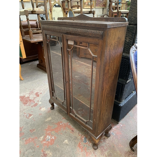 95 - An early 20th century carved oak display cabinet on cabriole supports - approx. 111cm high x 77cm wi... 