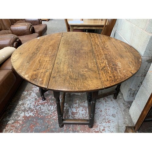 5 - A Georgian oak drop leaf gate leg dining table - approx. 74cm high x 128cm wide x 134cm long