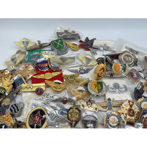 2159 - A large collection of military badges to include Russian, US Air Force wings etc.