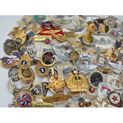 2159 - A large collection of military badges to include Russian, US Air Force wings etc.