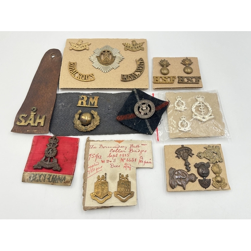 2162 - A collection of military badges and shoulder titles to include Royal Scots, Royal Marines etc.