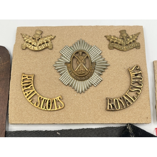 2162 - A collection of military badges and shoulder titles to include Royal Scots, Royal Marines etc.