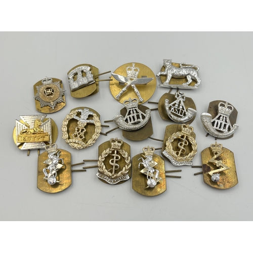 2165 - A collection of military cap badges with brass plates