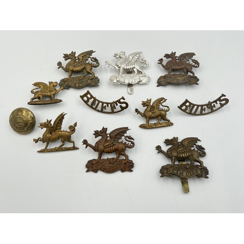 2177 - A collection of The Buffs cap badges, shoulder titles and buttons