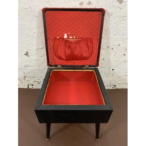 32 - A mid 20th century black vinyl and red fabric upholstered sewing stool on atomic supports - approx. ... 