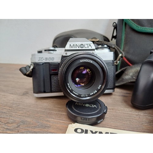 717 - Four cameras, one cased Minolta X-300 
35mm SLR fitted with MD 1:1.7 50mm, one cased Olympus iS-1000... 