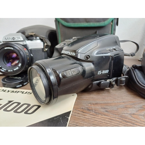 717 - Four cameras, one cased Minolta X-300 
35mm SLR fitted with MD 1:1.7 50mm, one cased Olympus iS-1000... 