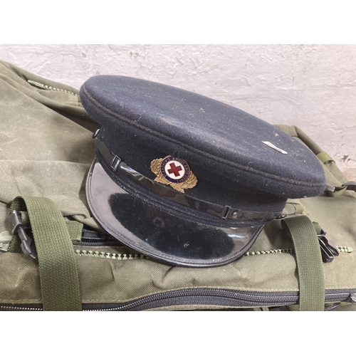 570 - A large quantity of military style rucksacks together with a St. Andrews Ambulance Corps peaked cap