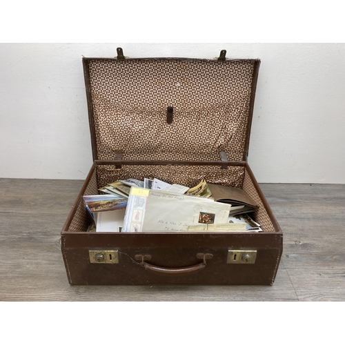 580 - A vintage brown leather suitcase containing a collection of first day covers, postcards and letters