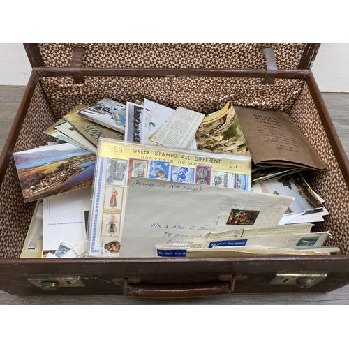 580 - A vintage brown leather suitcase containing a collection of first day covers, postcards and letters