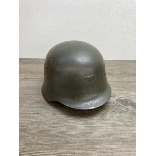 635B - Three pieces of militaria, one No.4 gas mask and two WWII helmets