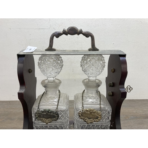 640 - A vintage mahogany presentation tantalus with two pressed glass decanters -approx. 35cm high x 24cm ... 