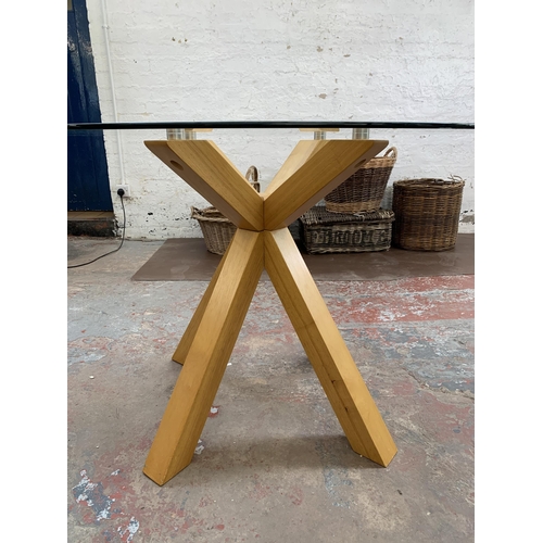 200 - A modern beech and glass top dining table - approx. 76cm high x 110cm diameter