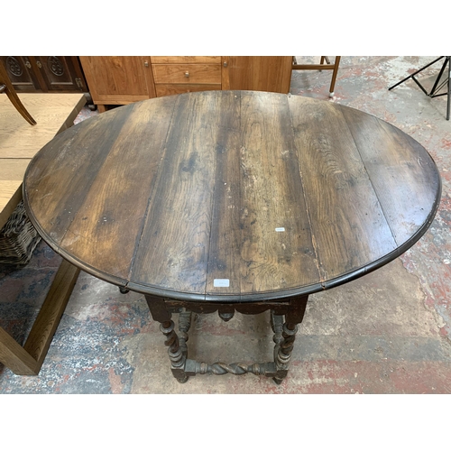203 - A 17th century and later oak drop leaf gate leg dining table on barley twist supports and three elm ... 