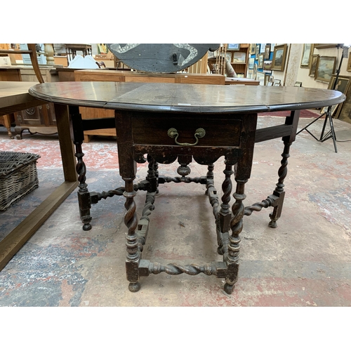 203 - A 17th century and later oak drop leaf gate leg dining table on barley twist supports and three elm ... 