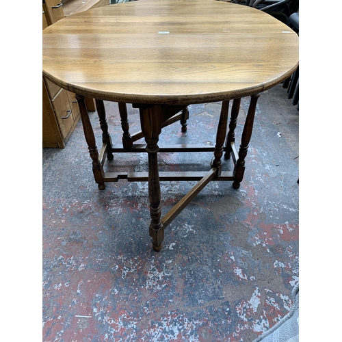 211 - A Georgian style oak drop leaf gate leg oval dining table - approx. 76cm high x 89cm wide x 133cm lo... 