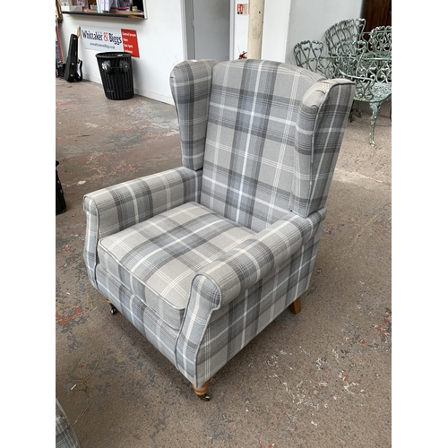 218 - A Dunelm grey striped upholstered wingback armchair on brass castors and matching storage footstool ... 