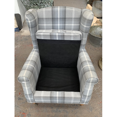 218 - A Dunelm grey striped upholstered wingback armchair on brass castors and matching storage footstool ... 