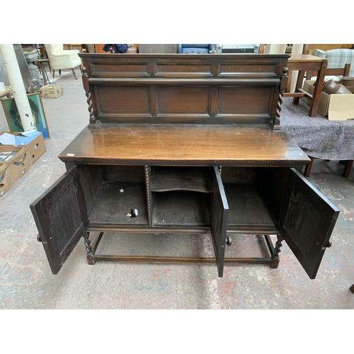 231 - An early 20th century oak sideboard on barley twist supports with lower stretcher, three cupboard do... 