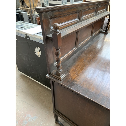 231 - An early 20th century oak sideboard on barley twist supports with lower stretcher, three cupboard do... 