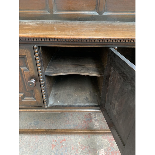 231 - An early 20th century oak sideboard on barley twist supports with lower stretcher, three cupboard do... 