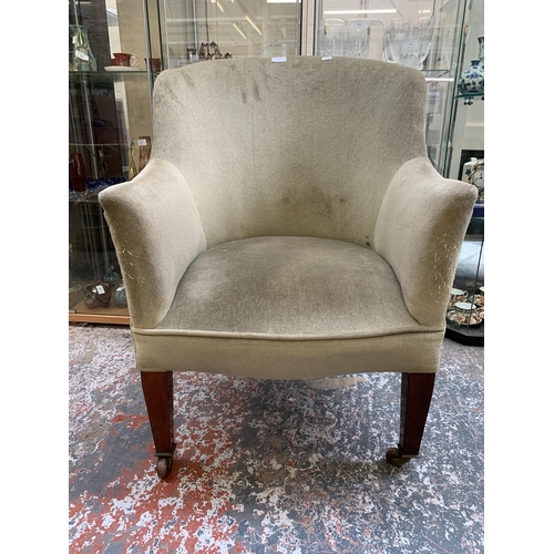 244 - An Edwardian green fabric upholstered armchair on mahogany tapered supports with ceramic and brass c... 