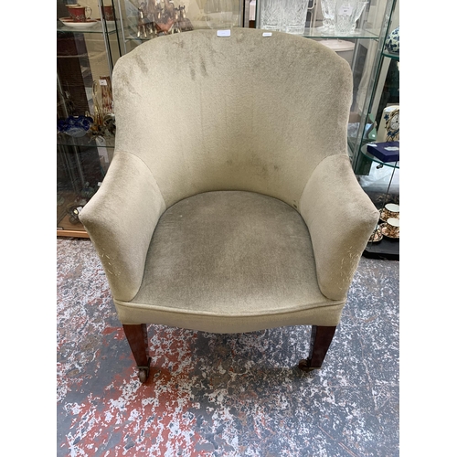 244 - An Edwardian green fabric upholstered armchair on mahogany tapered supports with ceramic and brass c... 