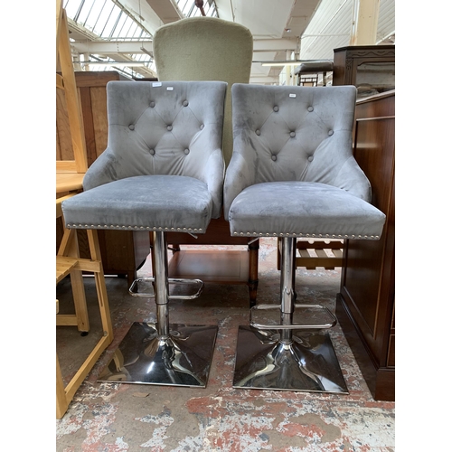 65 - A pair of modern grey fabric button back upholstered and chrome plated height adjustable bar stools