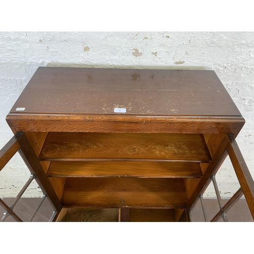 83 - An Art Deco oak display cabinet on baluster supports - approx. 123cm high x 76cm wide x 30cm deep