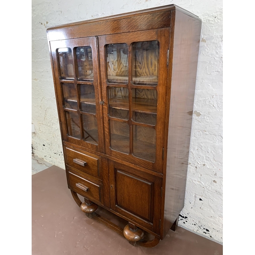 83 - An Art Deco oak display cabinet on baluster supports - approx. 123cm high x 76cm wide x 30cm deep