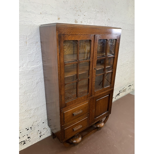 83 - An Art Deco oak display cabinet on baluster supports - approx. 123cm high x 76cm wide x 30cm deep