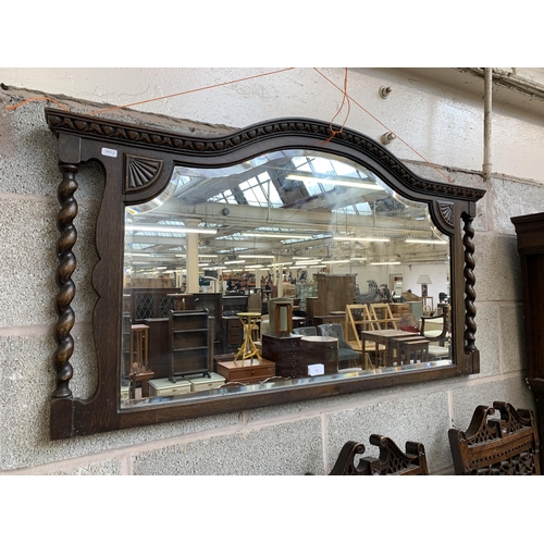 260 - An early 20th century oak framed bevelled edge overmantel mirror with barley twist supports - approx... 