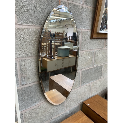 261 - A mid 20th century frameless bevelled edge oval wall mirror - approx. 95cm high x 45cm wide